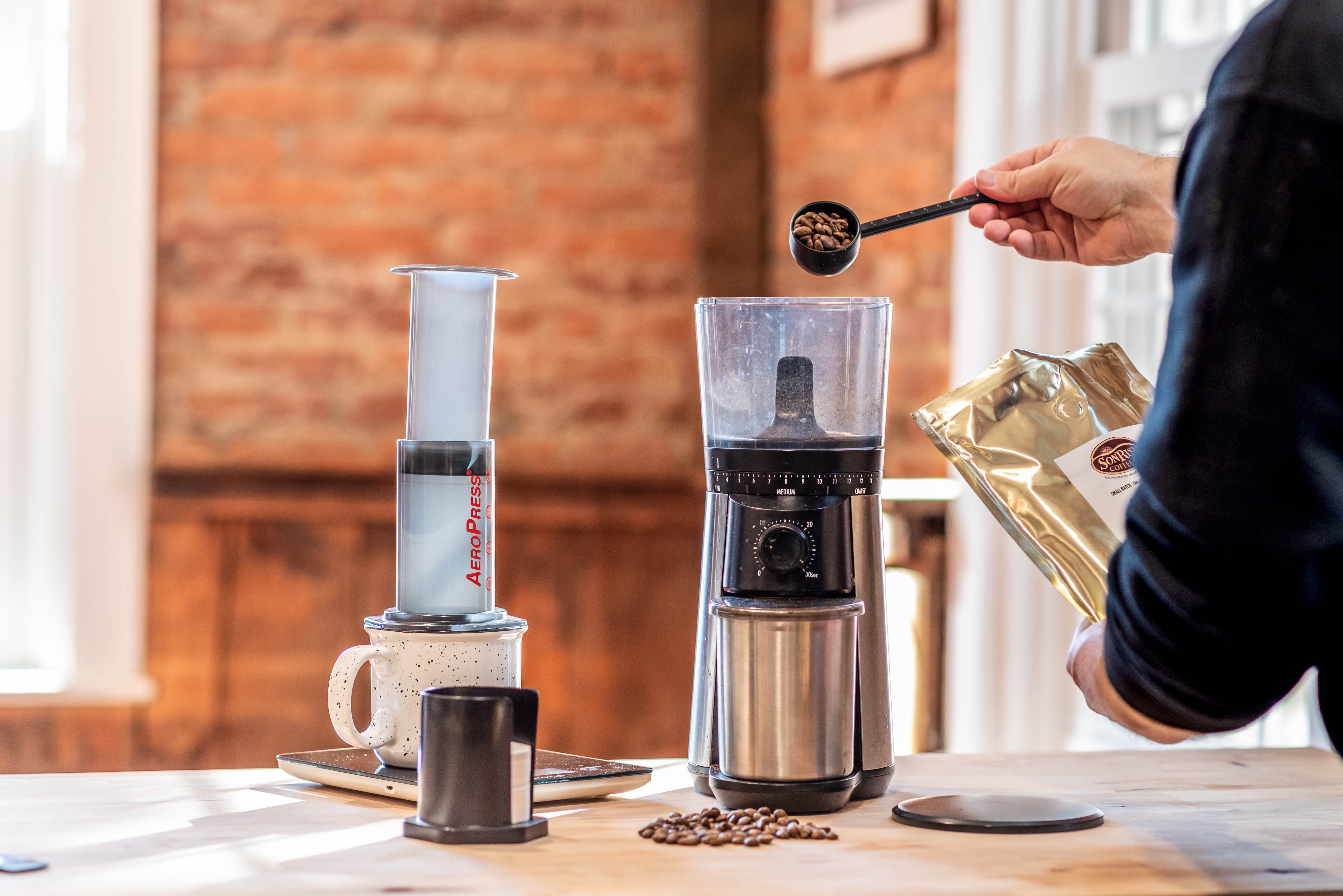 https://sonrisecoffeecompany.b-cdn.net/wp-content/uploads/Blog/AeroPress-Coffee/grinding-coffee-for-how-to-make-aeropress-coffee.jpg